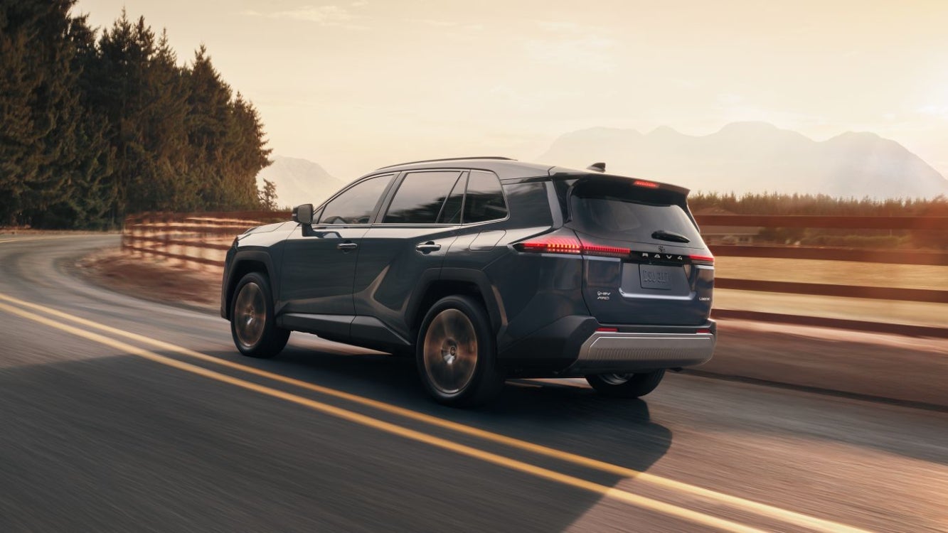 A blue Toyota RAV4 driving around a bend in the road.