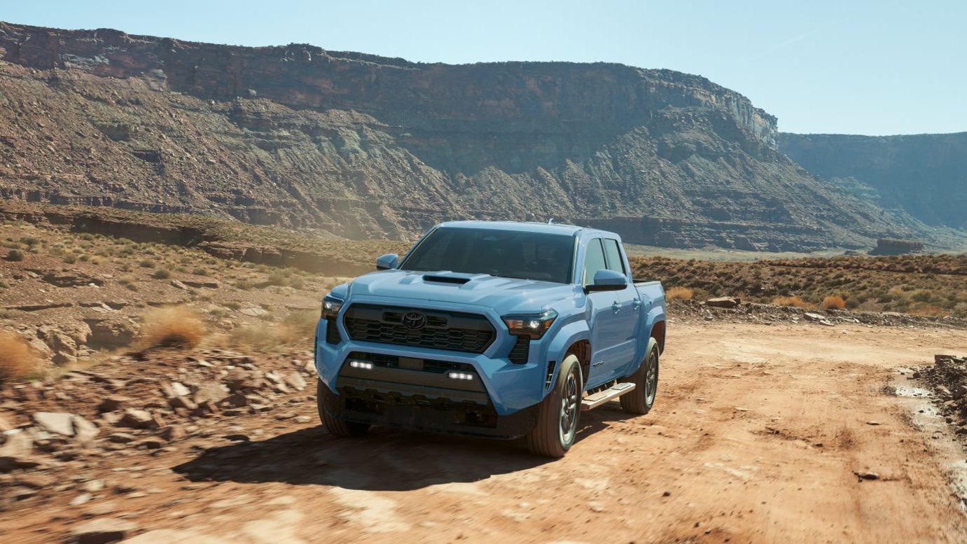 A blue Toyota Tacoma driving on a desert trail.