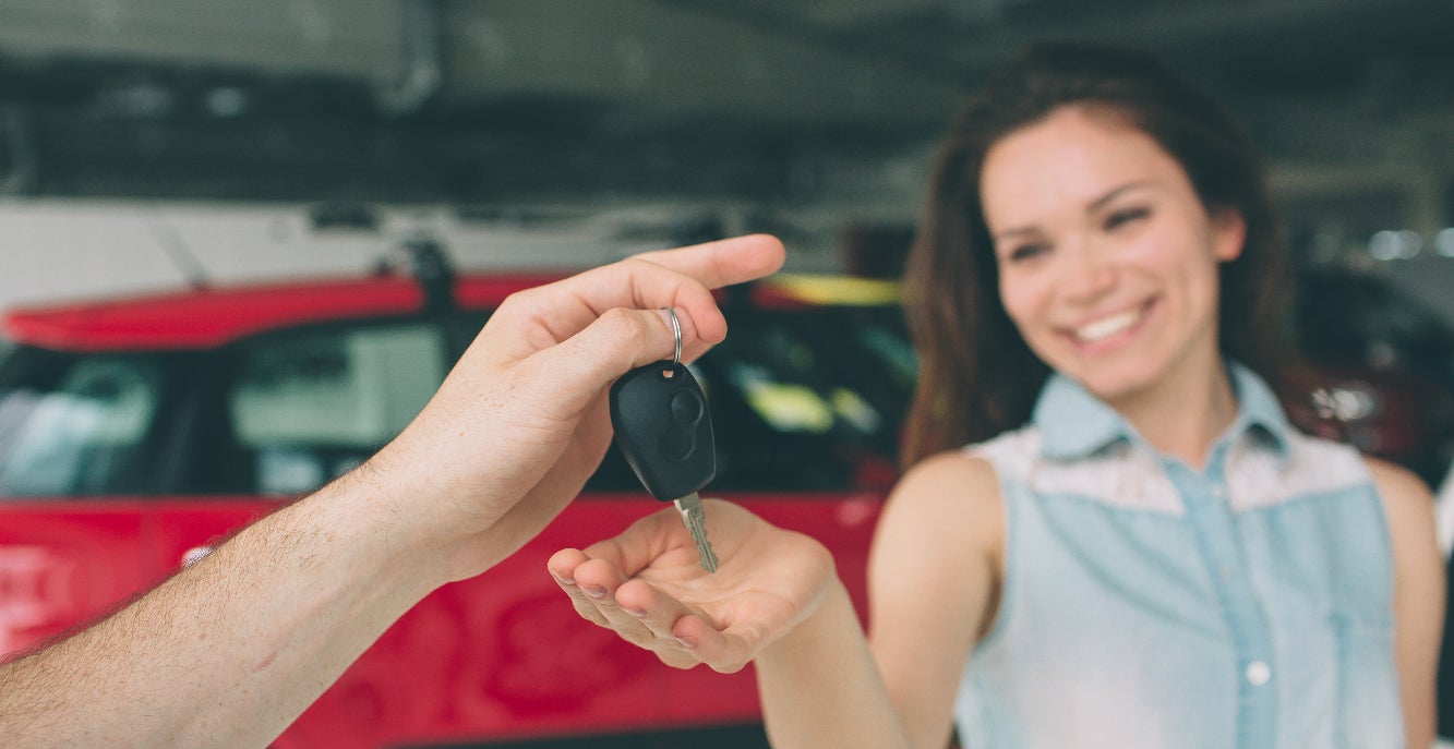 Smiling woman gets handed the keys to her used Toyota