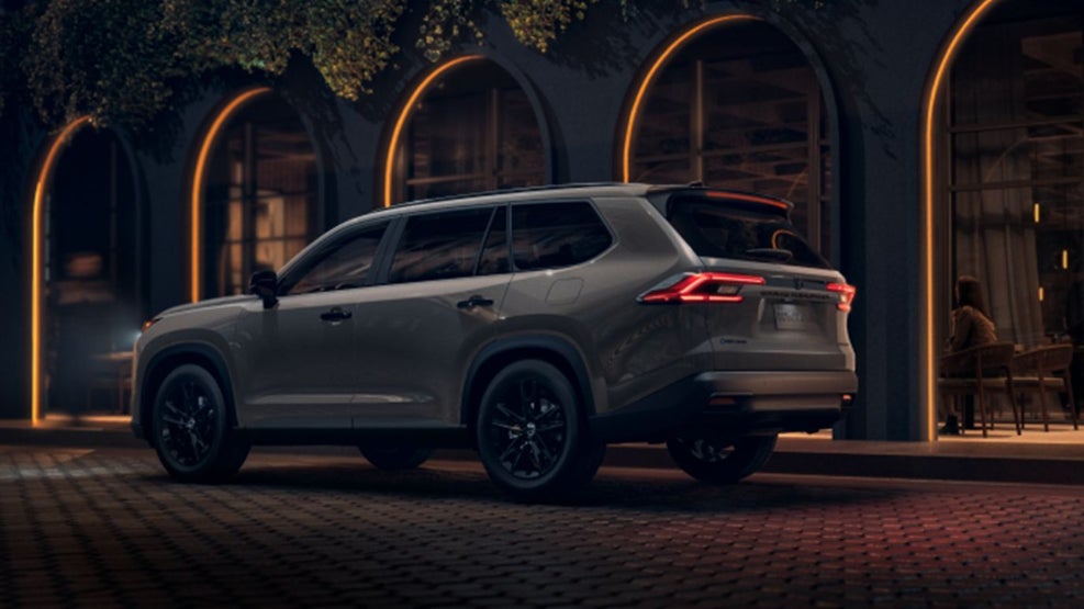 A gray Toyota Grand Highlander Hybrid parked outside a nice venue at night.