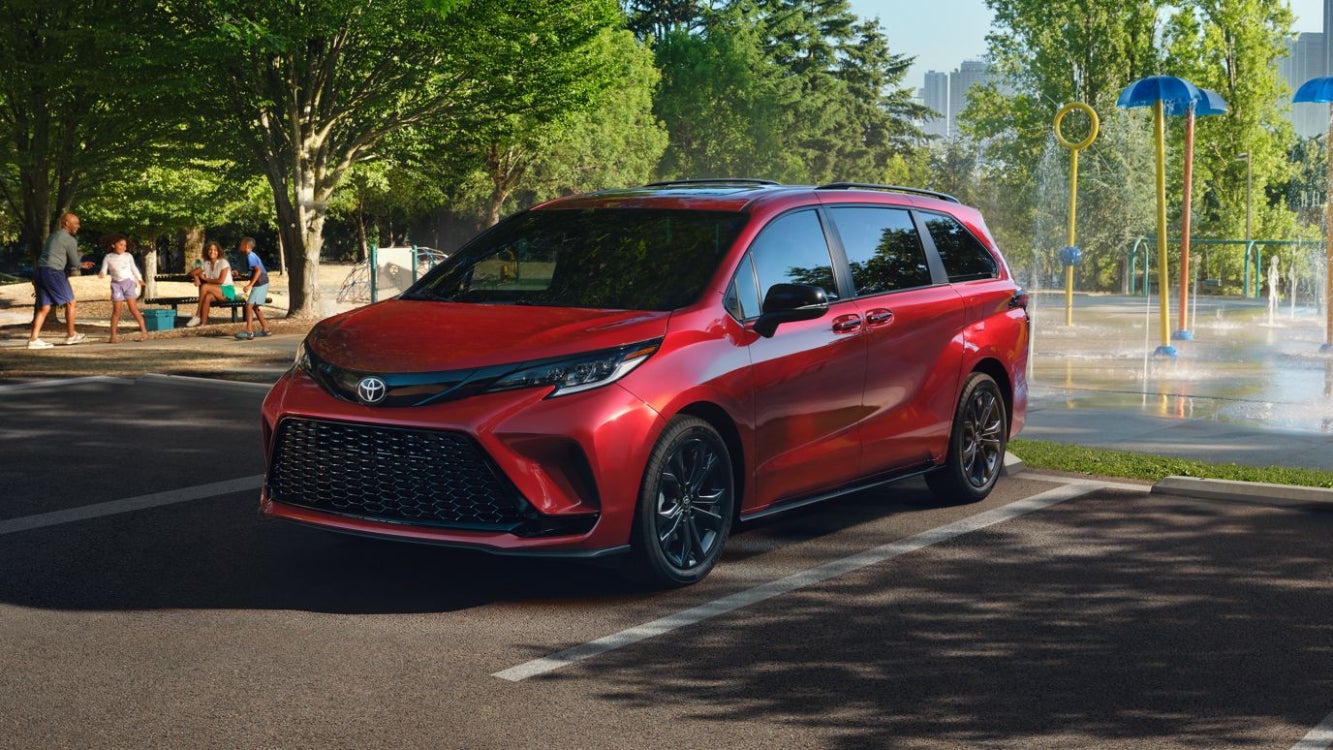 A red Toyota Sienna parked by a park.