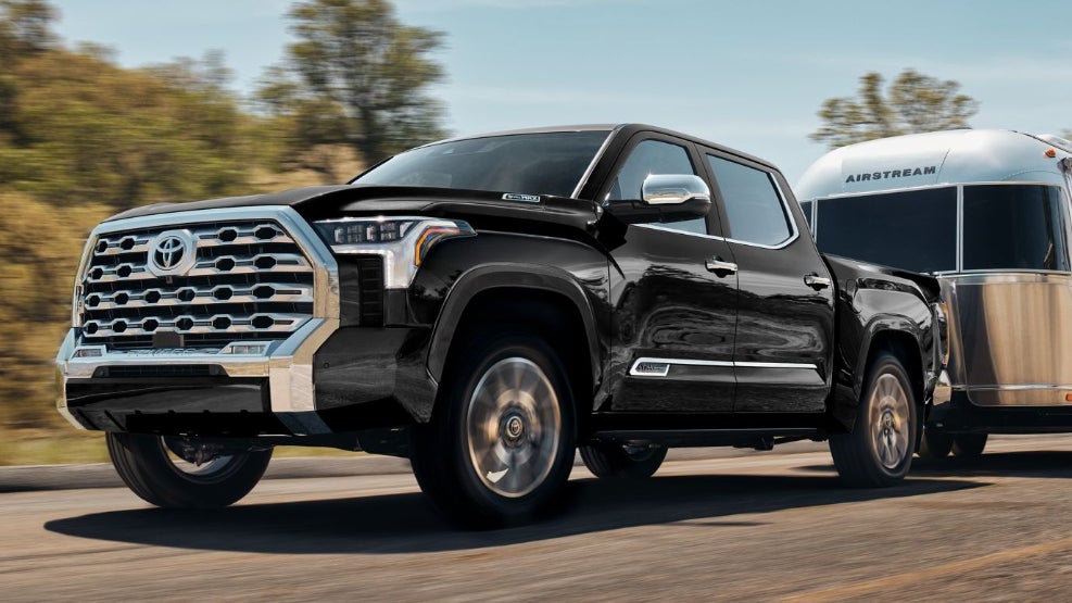 A black Toyota Tundra towing an Airstream trailer on the road.